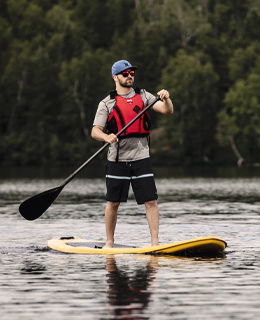 Un homme debout sur une planche à pagaie, sur un lac.