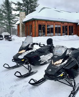 Deux motoneiges devant une pourvoirie.