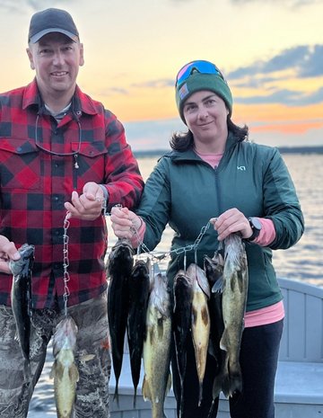 Un couple qui montre ses poissons devant un coucher de soleil