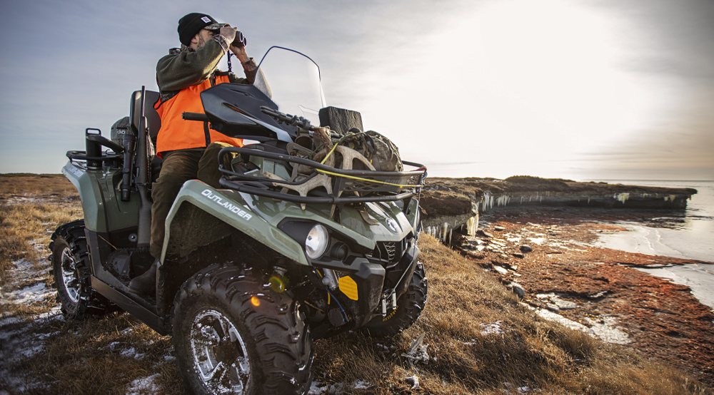 Un homme sur un quad regardant dans des jumelles.